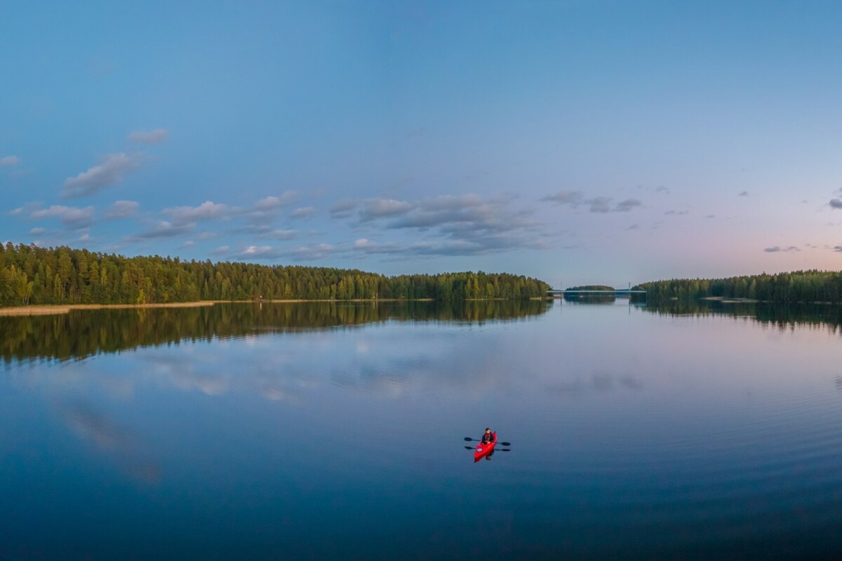 yksi kajakki peilityynellä järvellä taustalla metsää