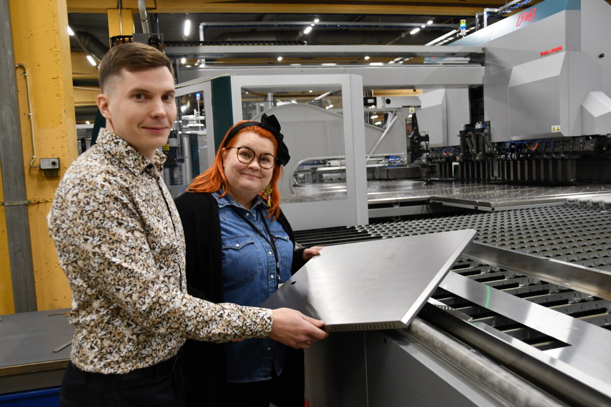 kaksi henkilöä pitelee käsissään isohkoa metallilevyä